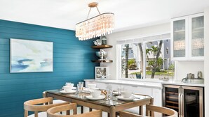 Une cuisine moderne avec un mur d’accent de couleur turquoise, une table à manger dressée avec de la vaisselle blanche et un four encastré.