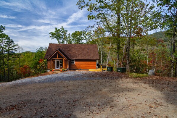 A cabin with a gravel driveway, surrounded by trees and a forested hillside. - Chillin Time mountain cabin near entrance to GSMNP (Bryson City)