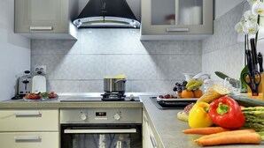 A modern kitchen with a built-in oven, a stovetop, and a range hood. - Magnificent villa with private pool, outdoor kitchen with barbecue (Divšici)