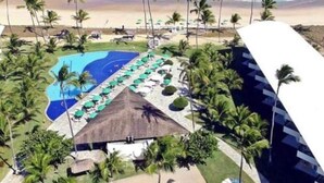 Un complexe hôtelier doté d’une piscine, d’une plage et de palmiers.