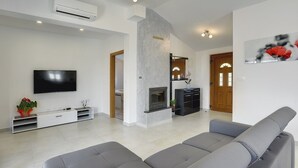 Una sala de estar moderna con un televisor de pantalla plana, sofás grises, una chimenea y un diseño minimalista.