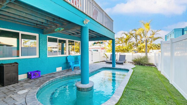 A backyard with a swimming pool, a covered patio, and a well-maintained lawn. - Sirena Del Mar | Newly Remodeled, Steps to Beach & Private Pool (Holmes Beach)