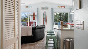 A compact kitchen with a black leather sofa, a small bar area, and a view of the outside. - Sirena Del Mar | Newly Remodeled, Steps to Beach & Private Pool (Holmes Beach)