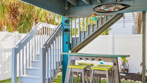A wooden staircase with white railings and a table with green stools. - Sirena Del Mar | Newly Remodeled, Steps to Beach & Private Pool (Holmes Beach)