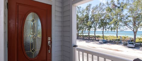 A wooden door with a glass panel and a white porch railing.