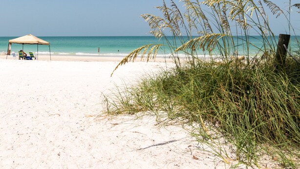 Une plage avec une tente et des chaises longues.