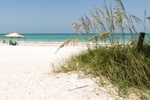 A beach with a tent and lounge chairs.