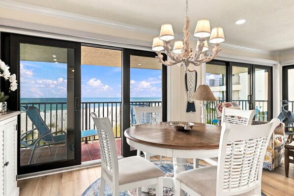 A dining area with a round table, chairs, and a chandelier.