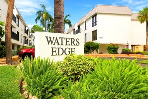 Skilt for 'WATERS EDGE' med en bygning i baggrunden.