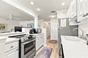 A modern kitchen with white cabinetry, stainless steel appliances, and a central island.