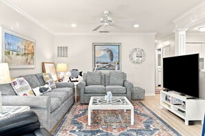 A living room with a gray sofa, a coffee table, a TV, and a patterned rug.