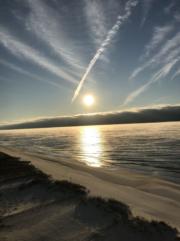 A beach with a sandy shoreline and a clear sky with the sun low on the horizon. - Leeway RE, Beautiful Gulf Front Condo (Gulf Shores)