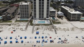 Een hotel aan het strand met meerdere gebouwen, een zwembad en strandparasols.