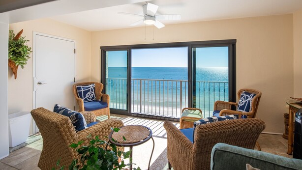 Een balkon met rieten meubilair, een plafondventilator en uitzicht op de oceaan.