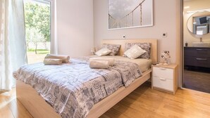 A bedroom with a bed, a bedside table, a mirror, and a window with curtains. - Villa for big demands with large pool, sauna, whirlpool, fitness equipment, billiards and professional outdoor kitchen (Liznjan)