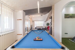 Et billardbord i et rum med udsigt til en opholdsstue, en radiator og en plante.