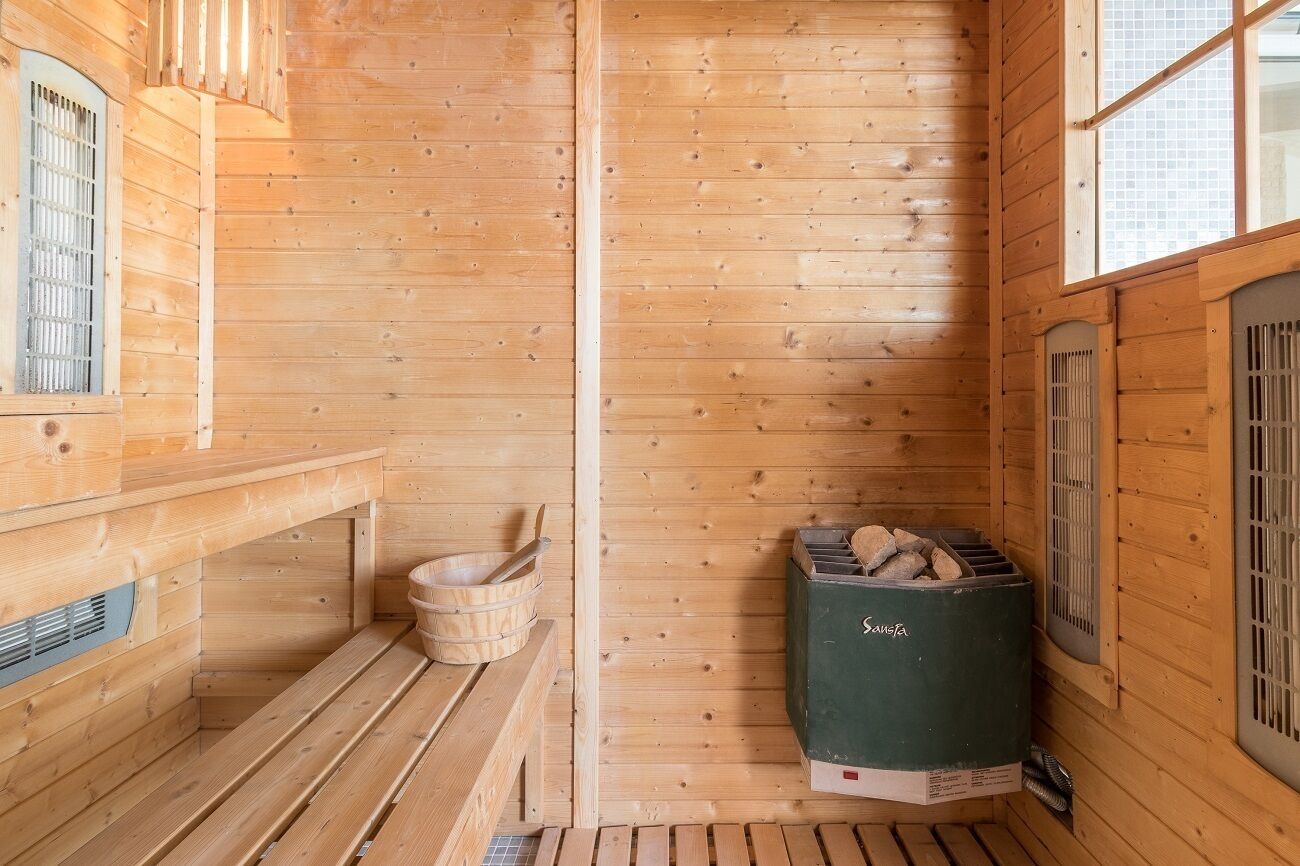 A wooden sauna room with benches, a sauna heater, and a window.