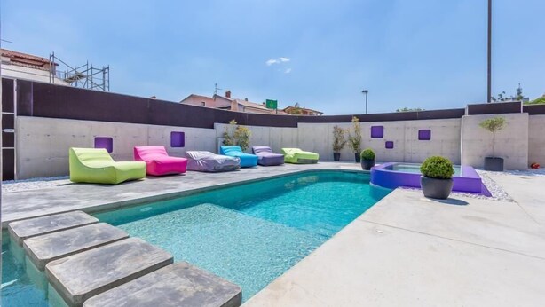 A swimming pool with colorful lounge chairs and a small hot tub.