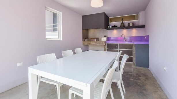 A modern kitchen with white cabinets, a purple countertop, and a white dining table with chairs.