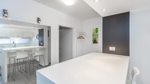 A modern kitchen with white cabinetry, a central island with bar stools, and recessed ceiling lighting.