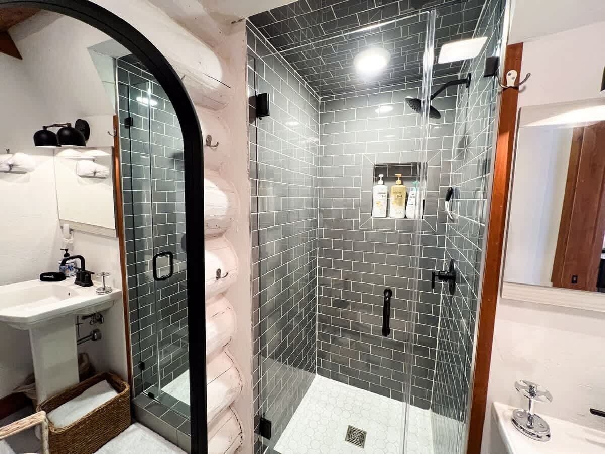 Ein Badezimmer mit Duschkabine, Waschbecken und Spiegel.
