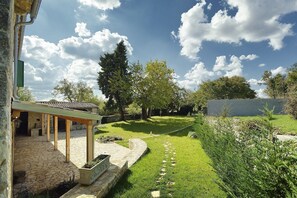 A covered patio area with stone flooring, a stone bench, and a small planter.
