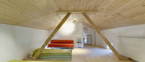 A room with a sloped ceiling, wooden beams, and a bed with green bedding.