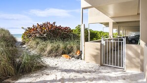 A beachfront property with a covered walkway leading to a gated entrance. - Sunset Terrace 201 · Gulf Front · Gulf Front (Bradenton Beach)