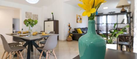 A modern dining area with a teal vase of yellow flowers on a table.