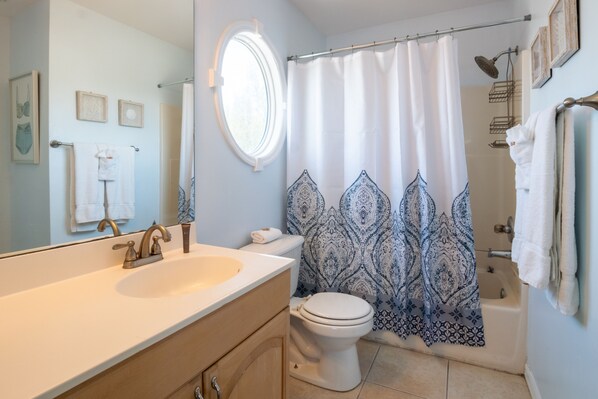 A bathroom with a large mirror, a sink, a toilet, and a shower curtain.