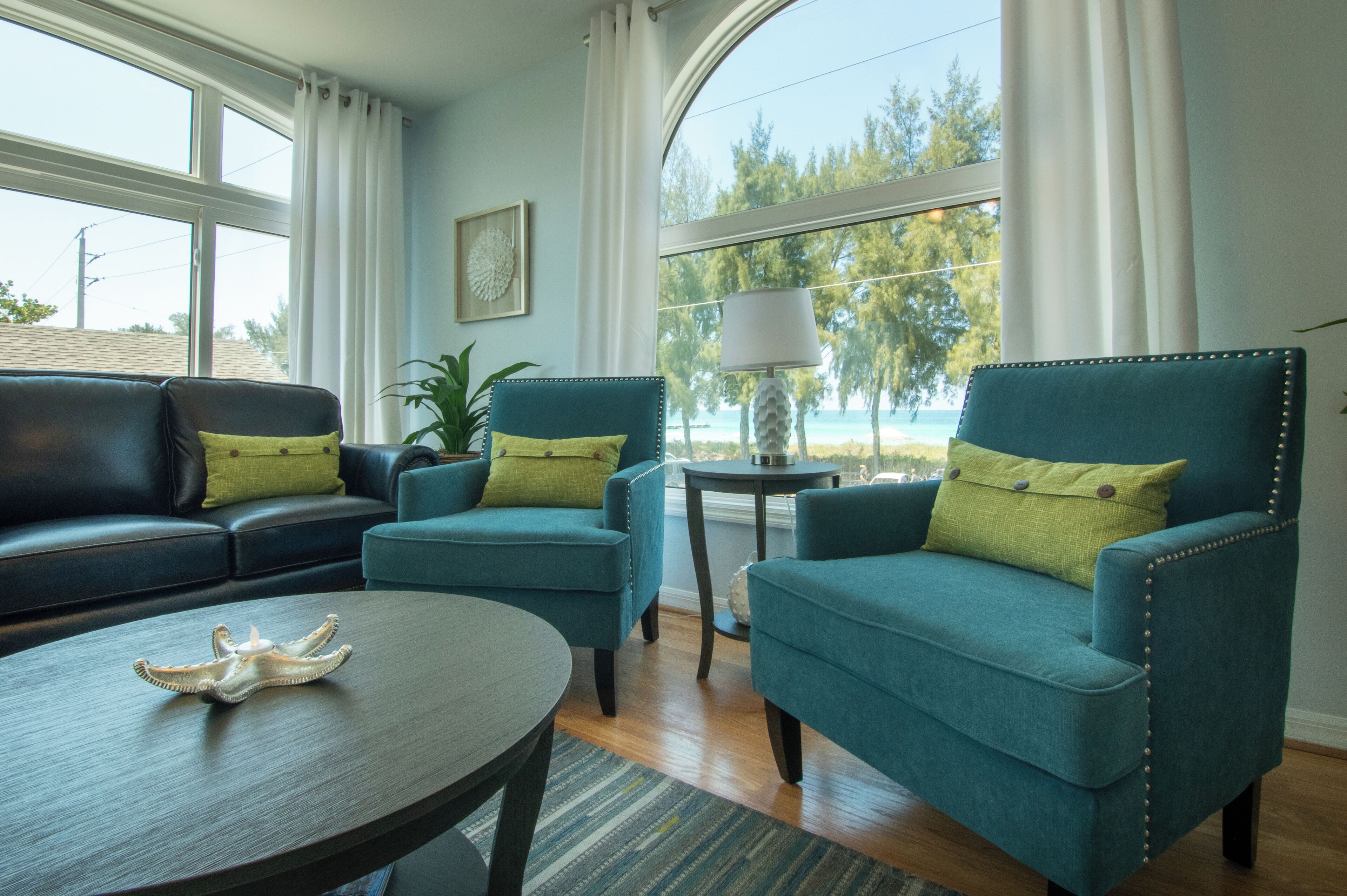 A living room with a sofa, two armchairs, a round coffee table, and a lamp.