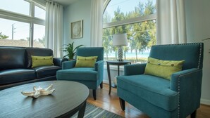A living room with a sofa, two armchairs, a round coffee table, and a lamp. - Dolphin Dance South · Gulf Views · 3-Night Min (Bradenton Beach)