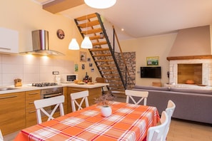 A modern kitchen with a central island, a dining area with a plaid tablecloth, and a stone fireplace. - Sunny villa with private pool and WiFi (Pula)