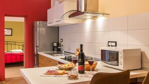 A modern kitchen with a microwave, a wine bottle, and a basket of bread.