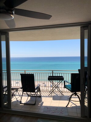 Een balkon met uitzicht op de oceaan, voorzien van stoelen en een plafondventilator.