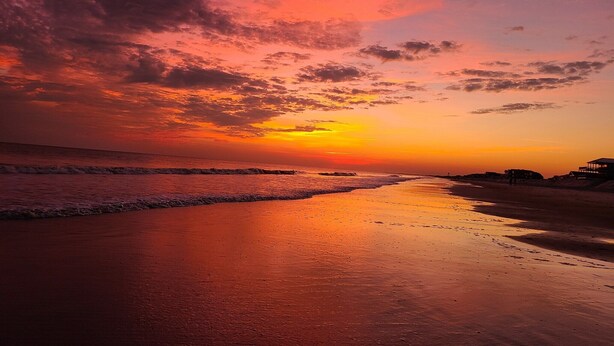 A beach at sunset with a clear sky and calm sea. - Family oasis beach retreat in quiet woodlands (Oak Island)