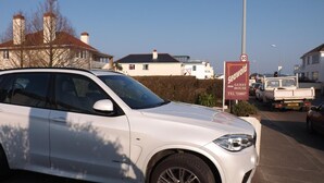 A white SUV parked in a residential area with a 'SeaWorld Guest House' sign visible in the background. - Seawold Guest House (St. Peter)