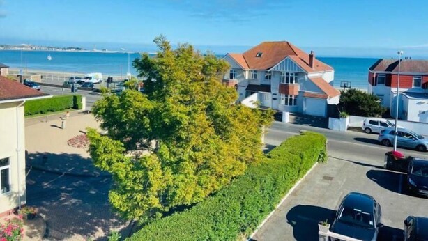 A coastal residential area with houses, a tree-lined driveway, and a view of the sea. - Seawold Guest House (St. Peter)