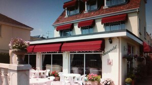 A seaside restaurant with outdoor seating, red awnings, and a sign reading "Seawood." - Seawold Guest House (St. Peter)