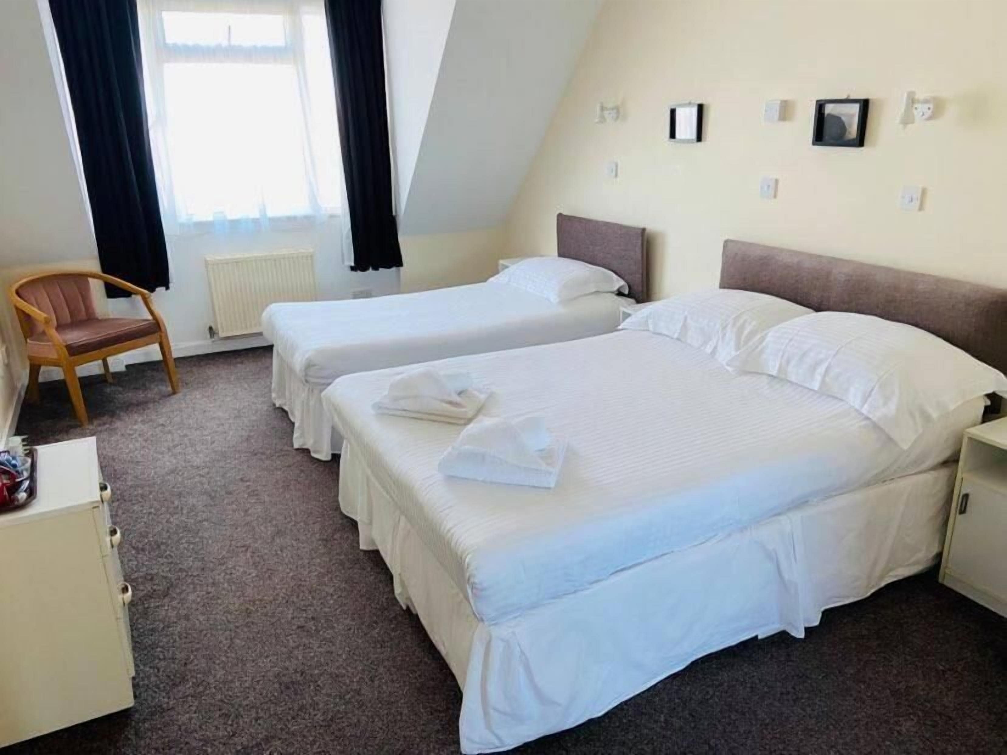 Una camera d'albergo con due letti singoli, una sedia, una scrivania e un termosifone.