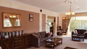 A spacious living room with a sofa, coffee table, and a bookshelf filled with books. - Seawold Guest House (St. Peter)