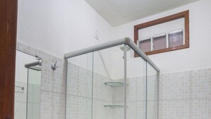 Un baño con ducha de vidrio, lavamanos e inodoro.