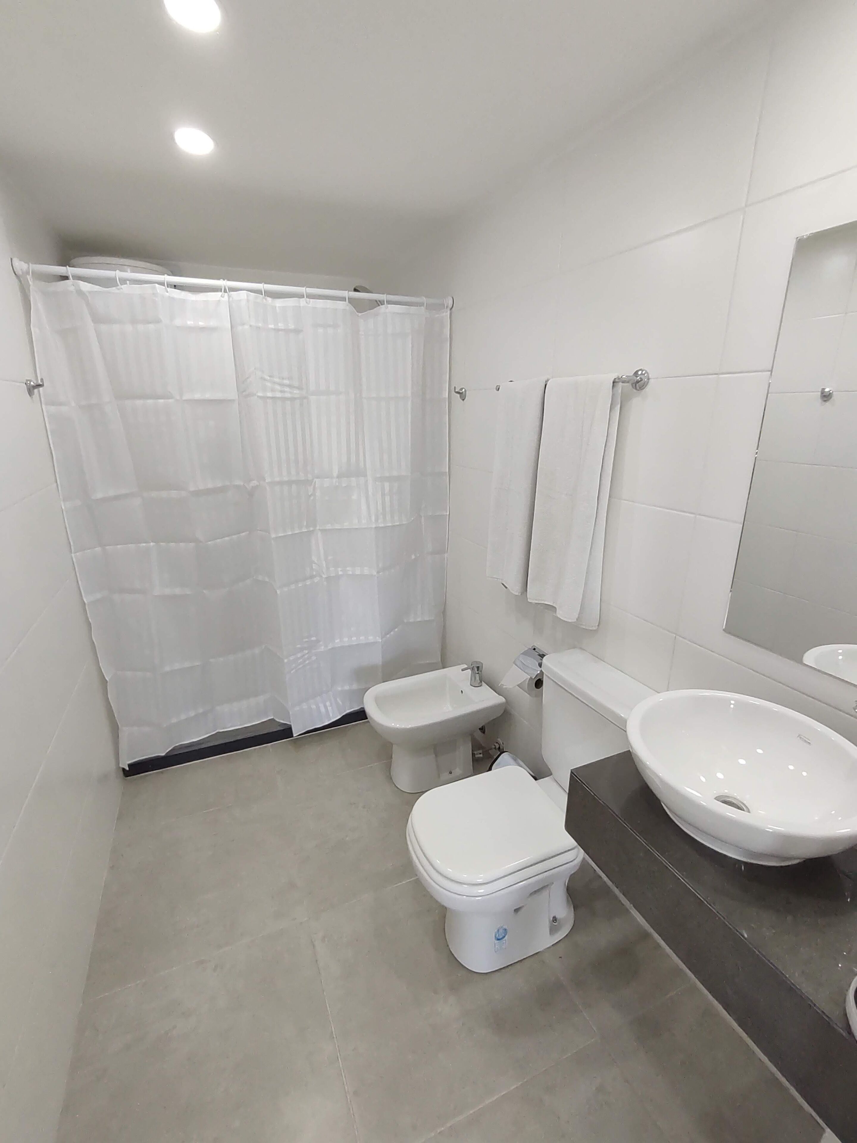 A modern bathroom with a toilet, bidet, and sink.