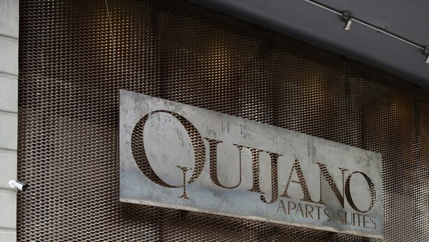 Un edificio con un letrero que dice "QUIJANO APARTS & SUITES".