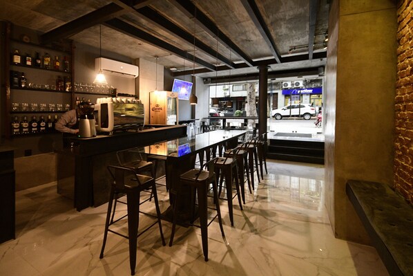 Zona de bar con mostrador, taburetes y una exhibición de botellas.