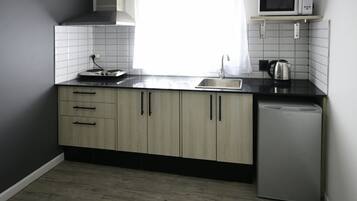 Una cocina moderna con lavavajillas, microondas y hervidor sobre la encimera.