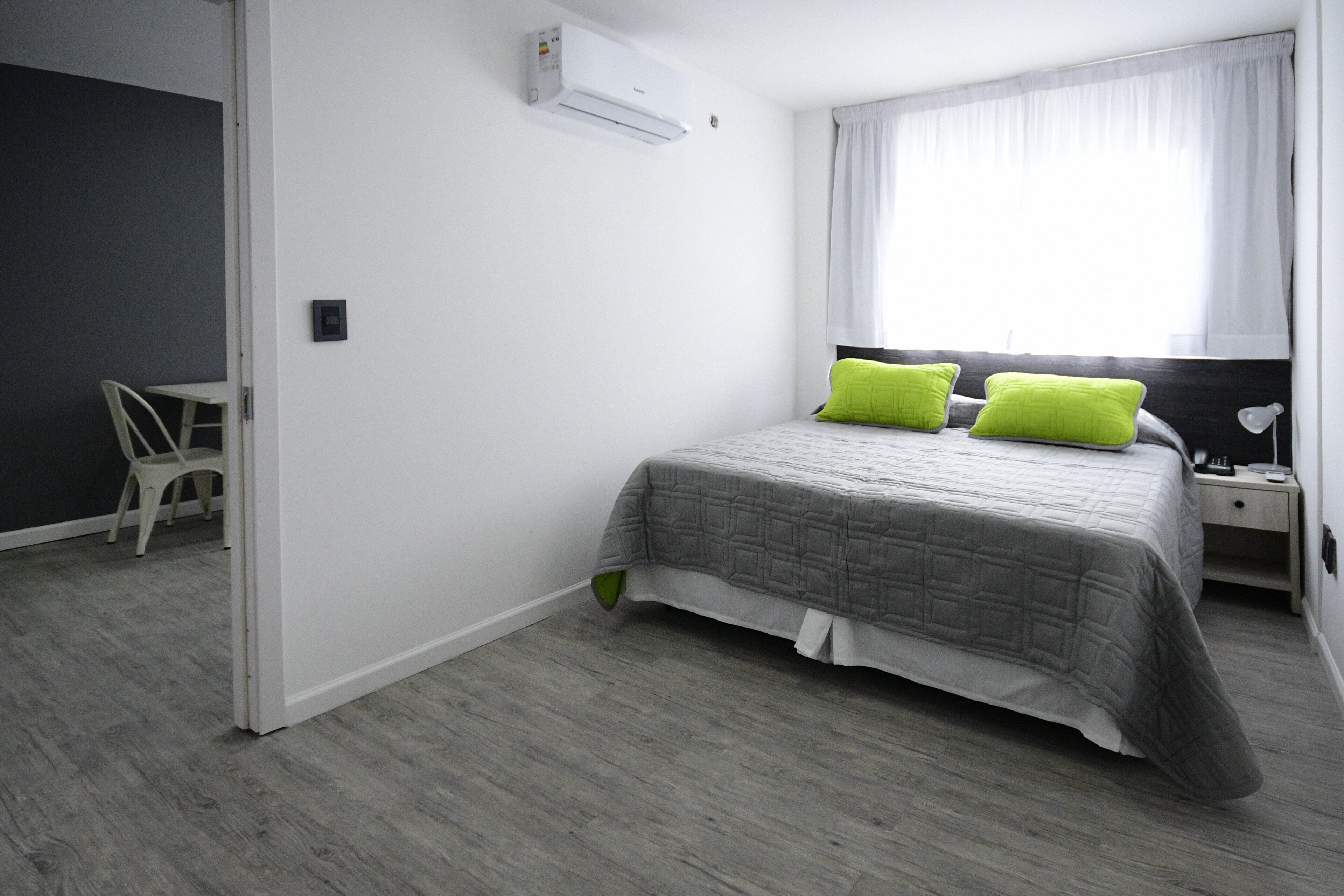 A bedroom with a bed, a bedside table, a chair, and a window with curtains.