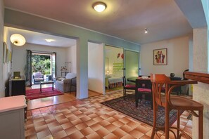 Amplia sala de estar con mesa de comedor, sillas y sofá. Hay un ventanal corredero que da a un balcón con vistas a zonas verdes.