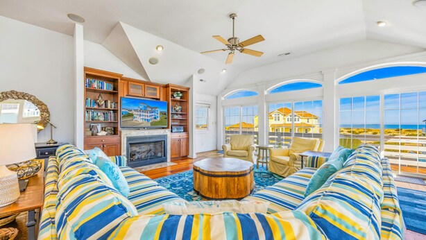 A spacious living room with a fireplace, a television, and a view of the ocean. - Premier Oceanfront Dog Friendly w/ Pool, Elevator, Hot Tub, Theater, Game Rooms (Salvo)
