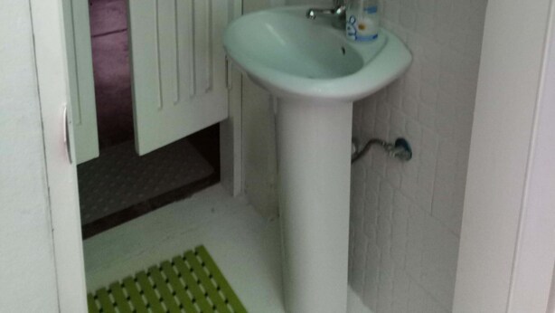 Une salle de bain avec un lavabo blanc, un miroir au-dessus et une étagère contenant des articles de toilette.